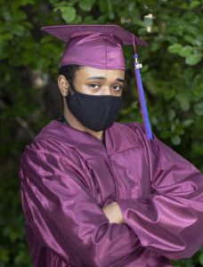 a young man in formal graduation gown and mortar board